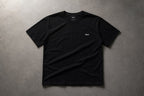 Black t-shirt flat lay on concrete with chest wordmark