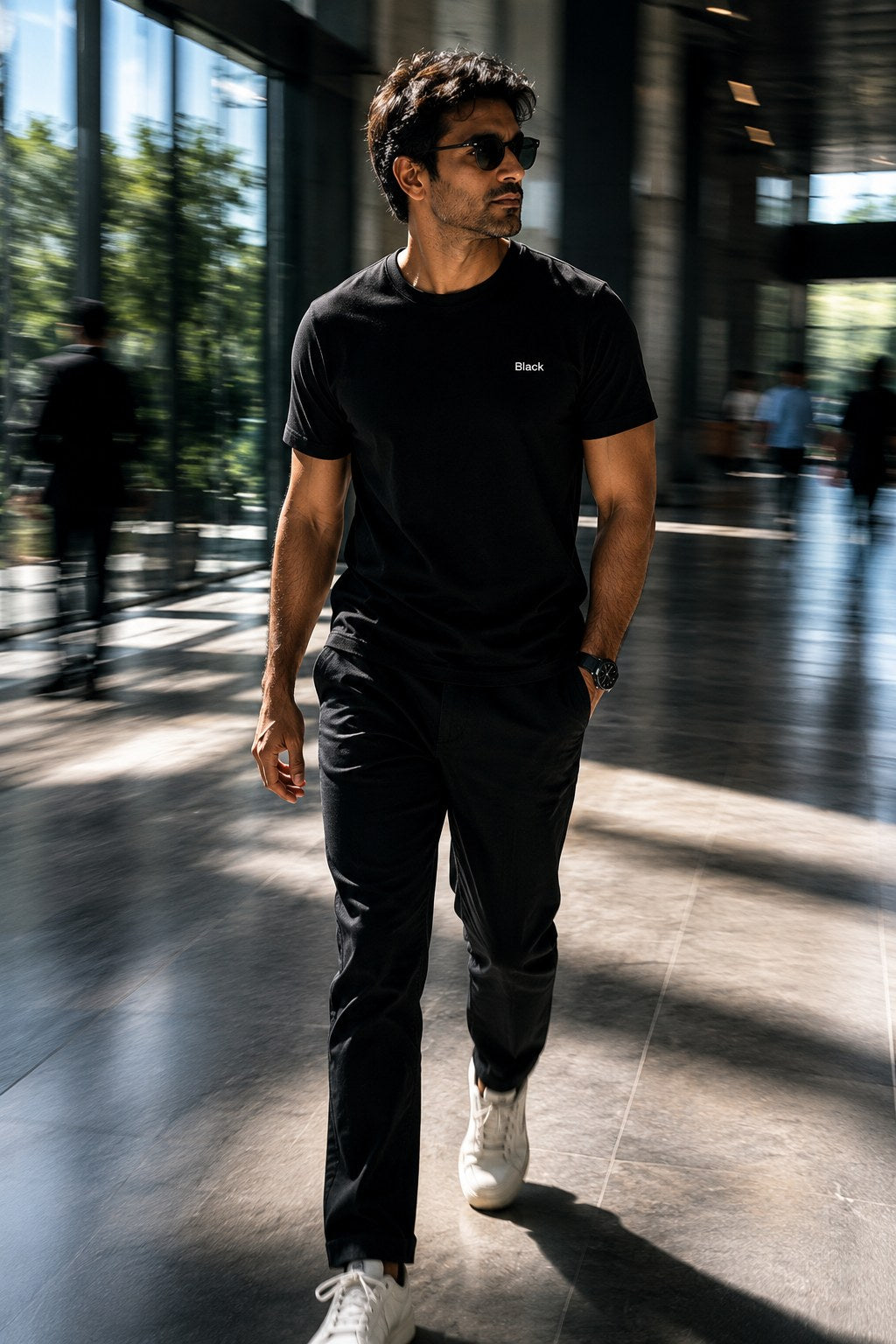 Man in Black tee walking through a sunlit atrium