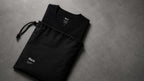 Folded Black tee beside the branded drawstring dust bag