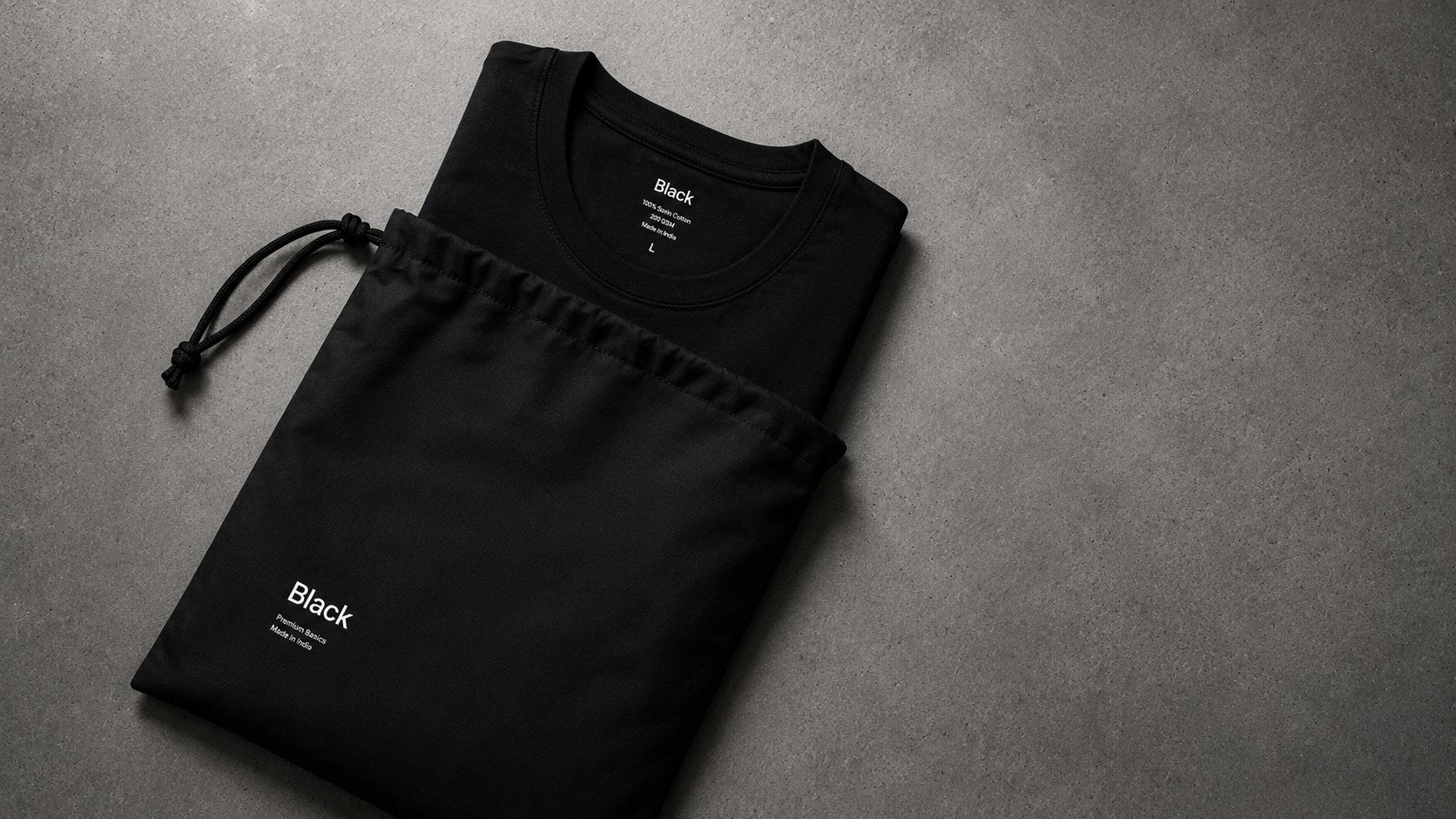 Folded Black tee beside the branded drawstring dust bag