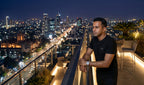Man wearing the Black tee on a rooftop at night with city skyline