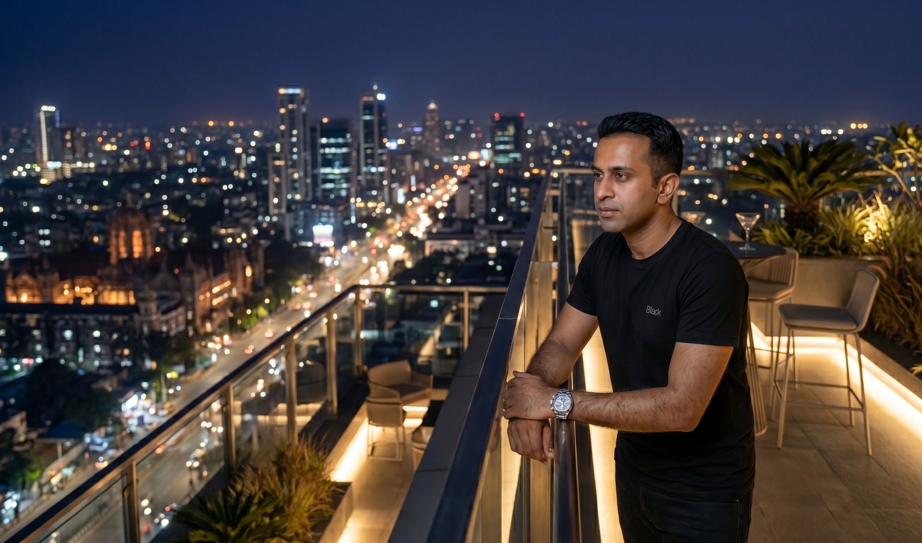 Man wearing the Black tee on a rooftop at night with city skyline