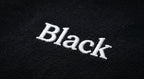 Close-up of white embroidered Black wordmark on the chest