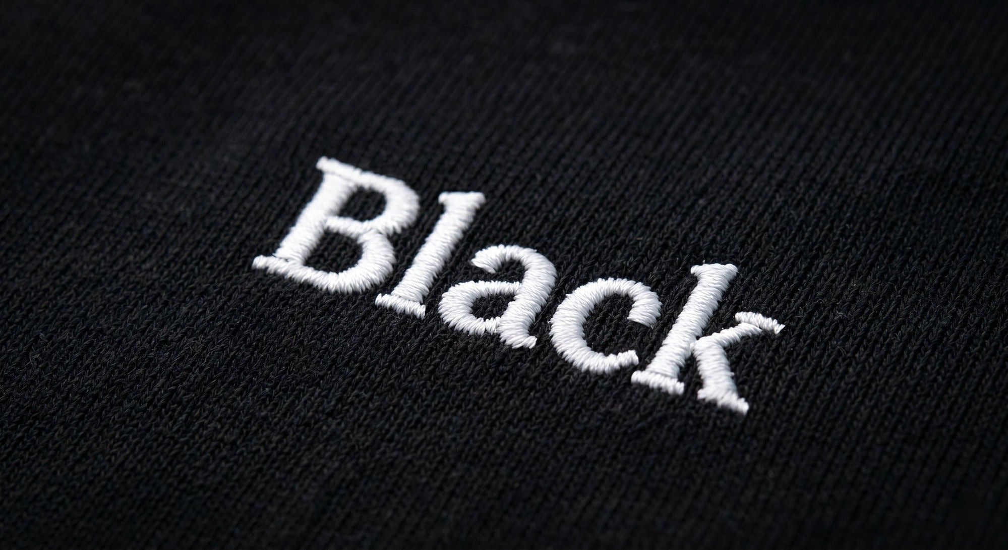 Close-up of white embroidered Black wordmark on the chest